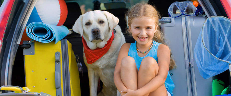 Girl sitting with white dog in back of SUV
